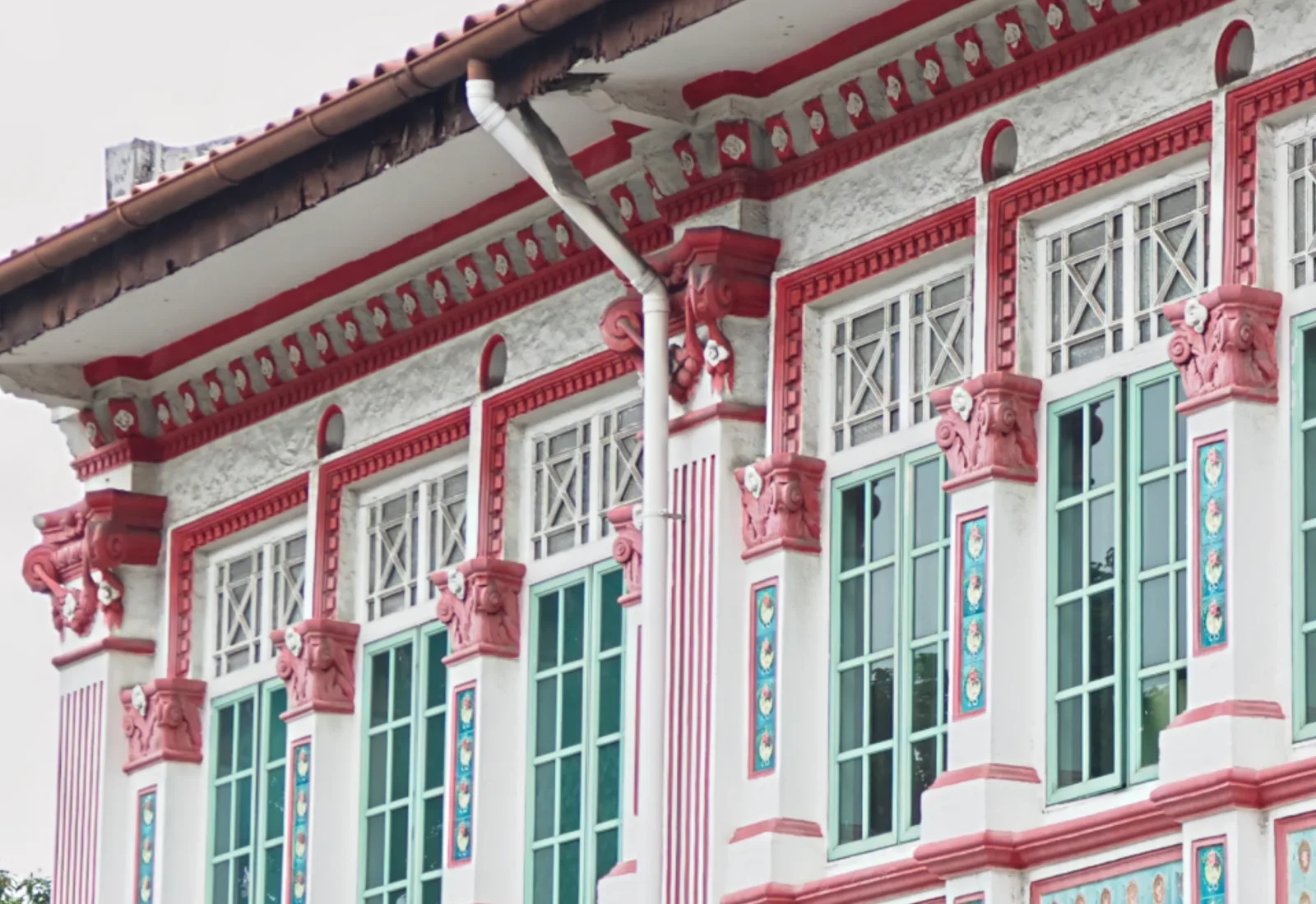 Ornate Singapore heritage facade with red trim and mint-green windows