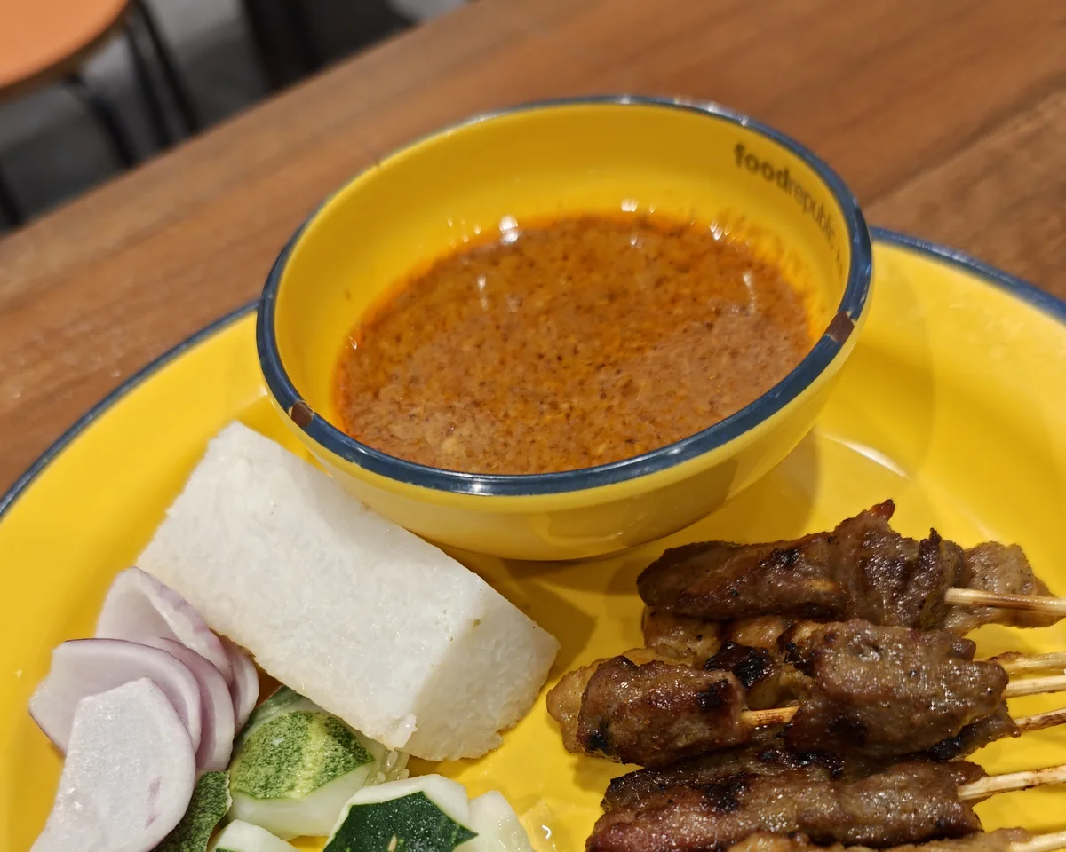 Plate of local satay with ketupat, cucumber and peanut sauce