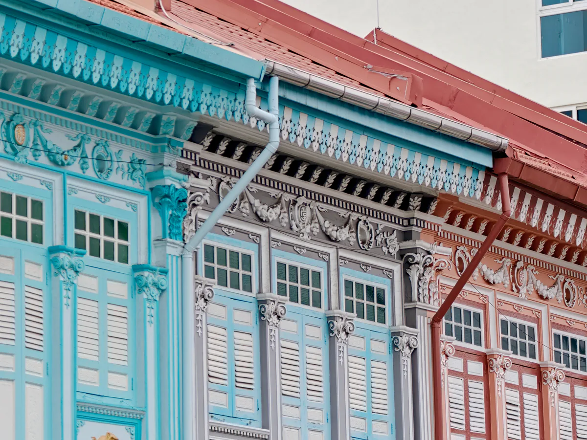 Turquoise, grey and coral Peranakan shophouse facades with carved decorative details