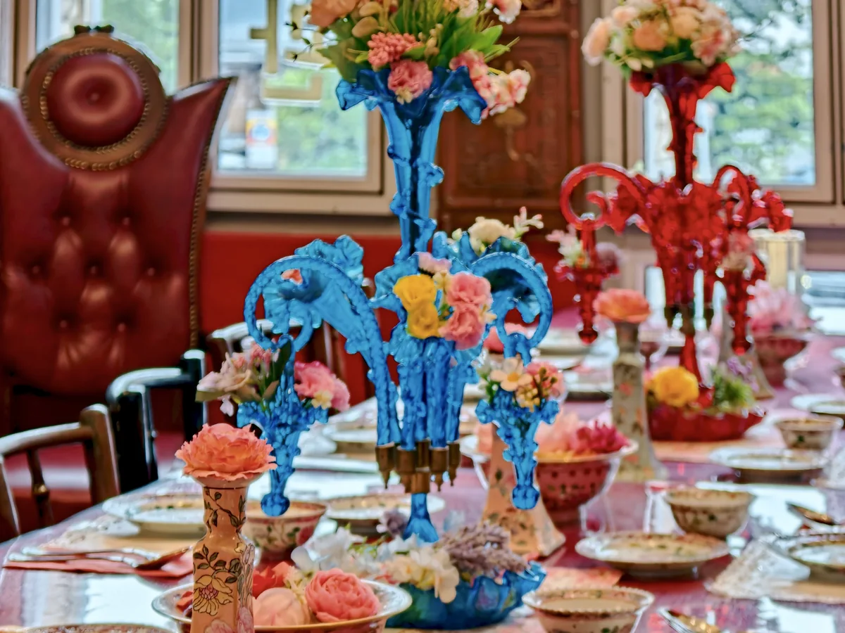 Peranakan dining table with colourful floral centrepieces and porcelain tableware